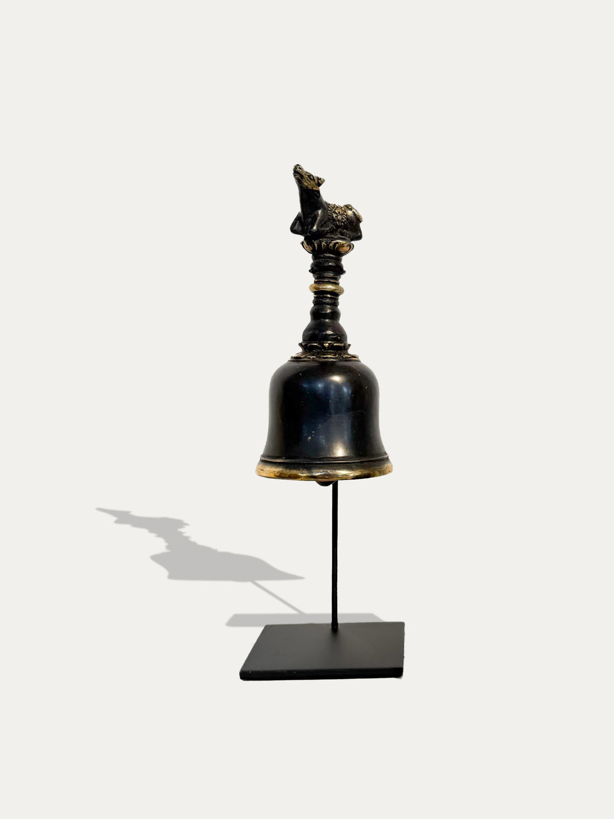 Vorderansicht der Ghanta-Tempelglocke aus Messing aus Bali mit verziertem Griff und schwarzem Metallständer.