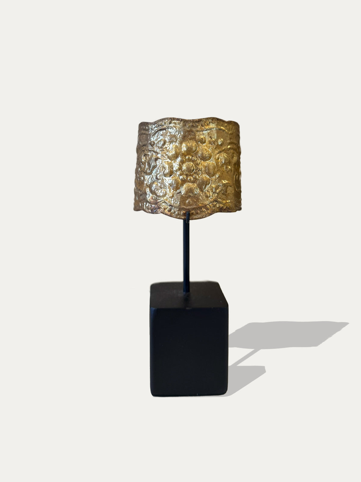 Sumatran brass cuff from Indonesia with hammered and embossed texture on black metal stand