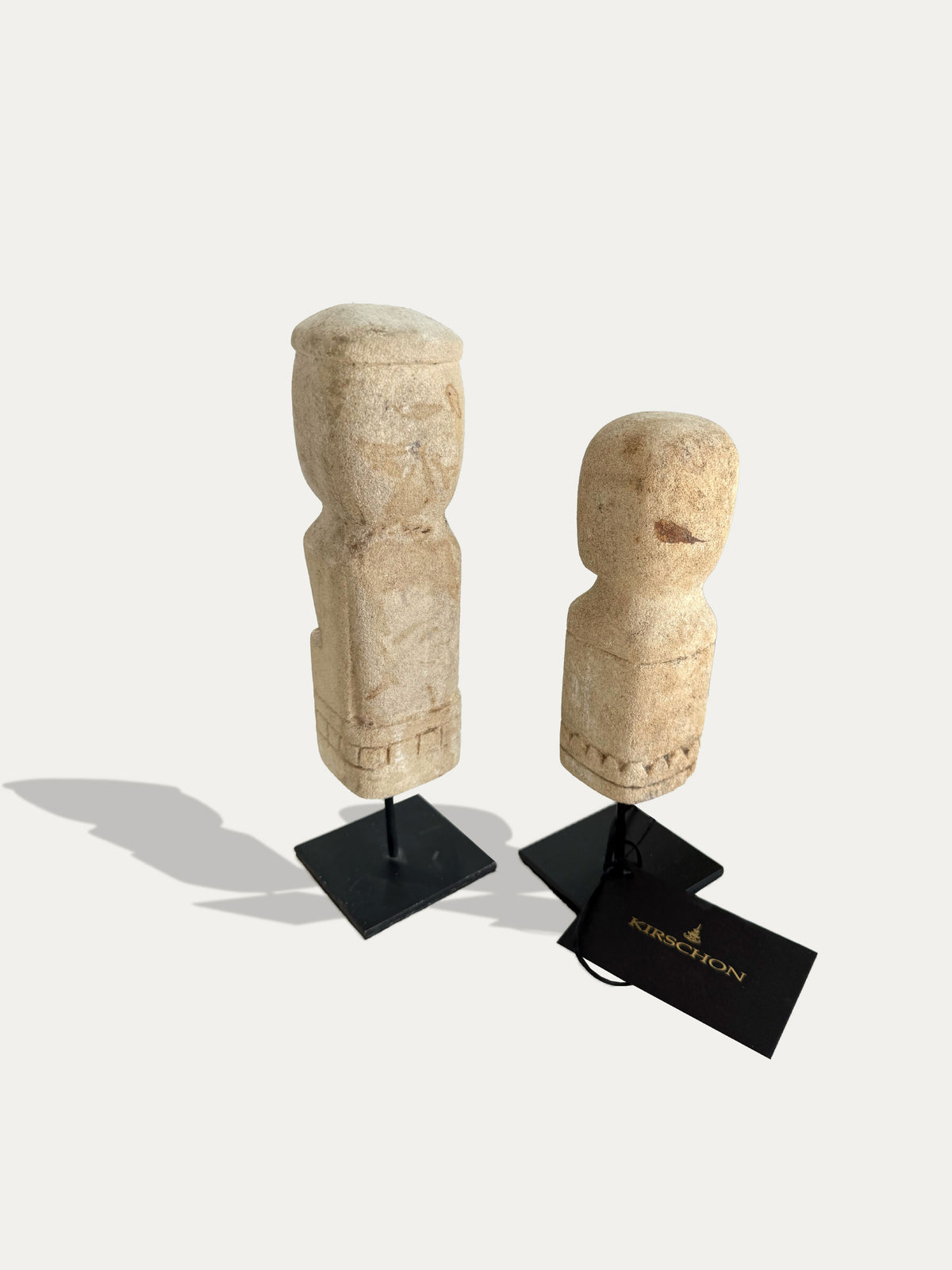 Rear view of the pair of Timor limestone statues, showing natural stone textures and carved details on black metal stands.