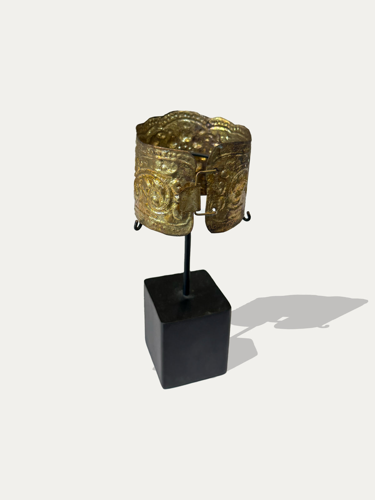 Traditional Sumatran brass cuff with textured surface on a blackened metal display stand