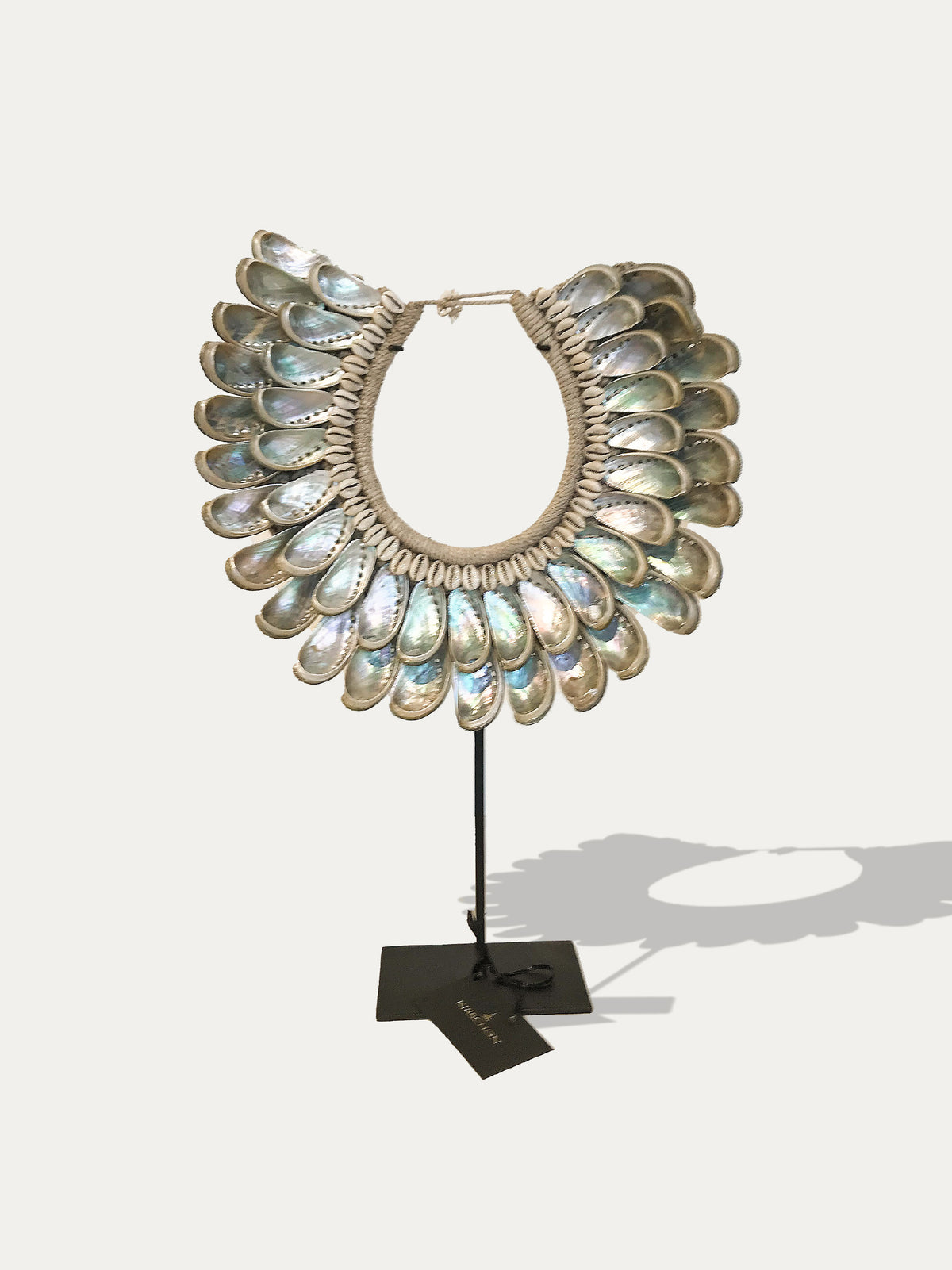 Front view of a Papua abalone shell necklace with natural fibre bindings, displayed on a black metal stand.