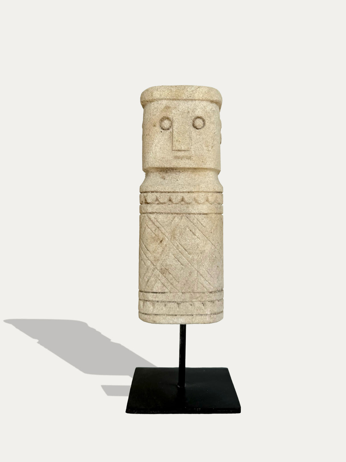 Hand-carved tribal limestone statue from Timor, Indonesia on black metal stand