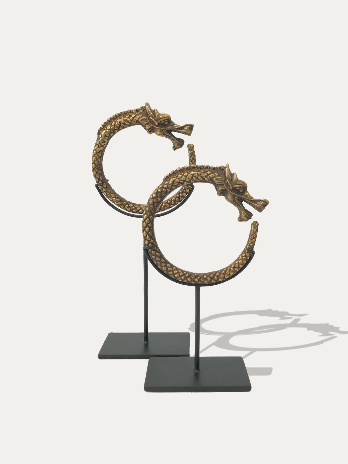Two brass Naga dragon bangles from Borneo with a Sumatran brass cuff displayed as Indonesian art objects