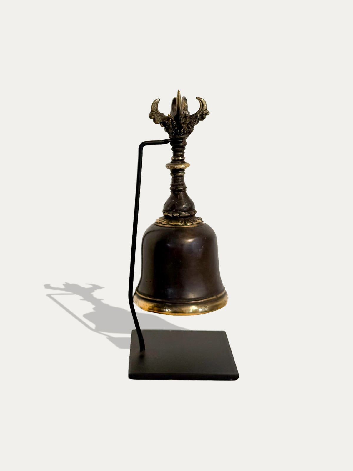 Vista posterior de la campana Ghanta balinesa de latón, que muestra el soporte curvo de metal negro